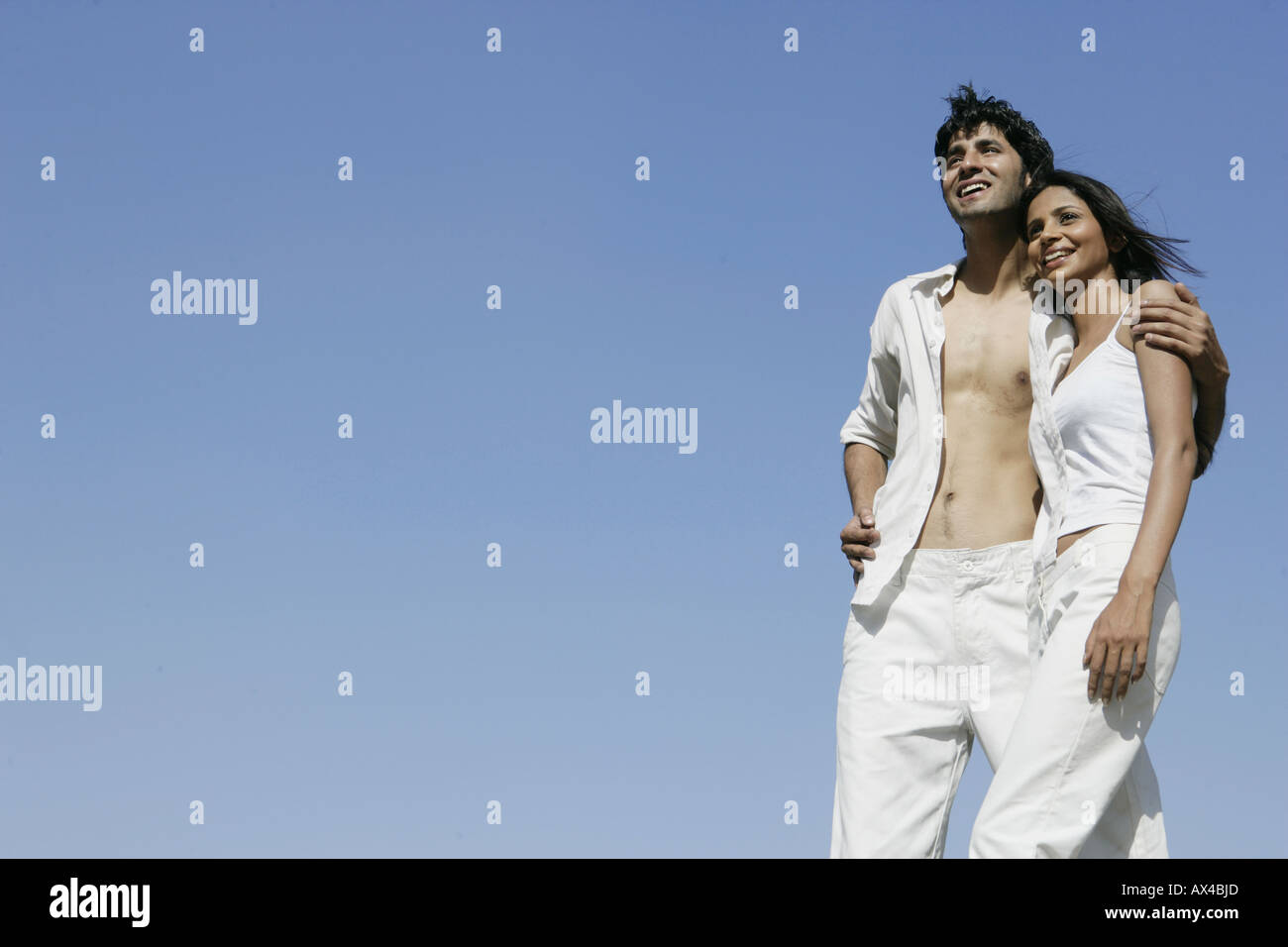 Low angle view of a young man standing with his girlfriend and smiling Stock Photo