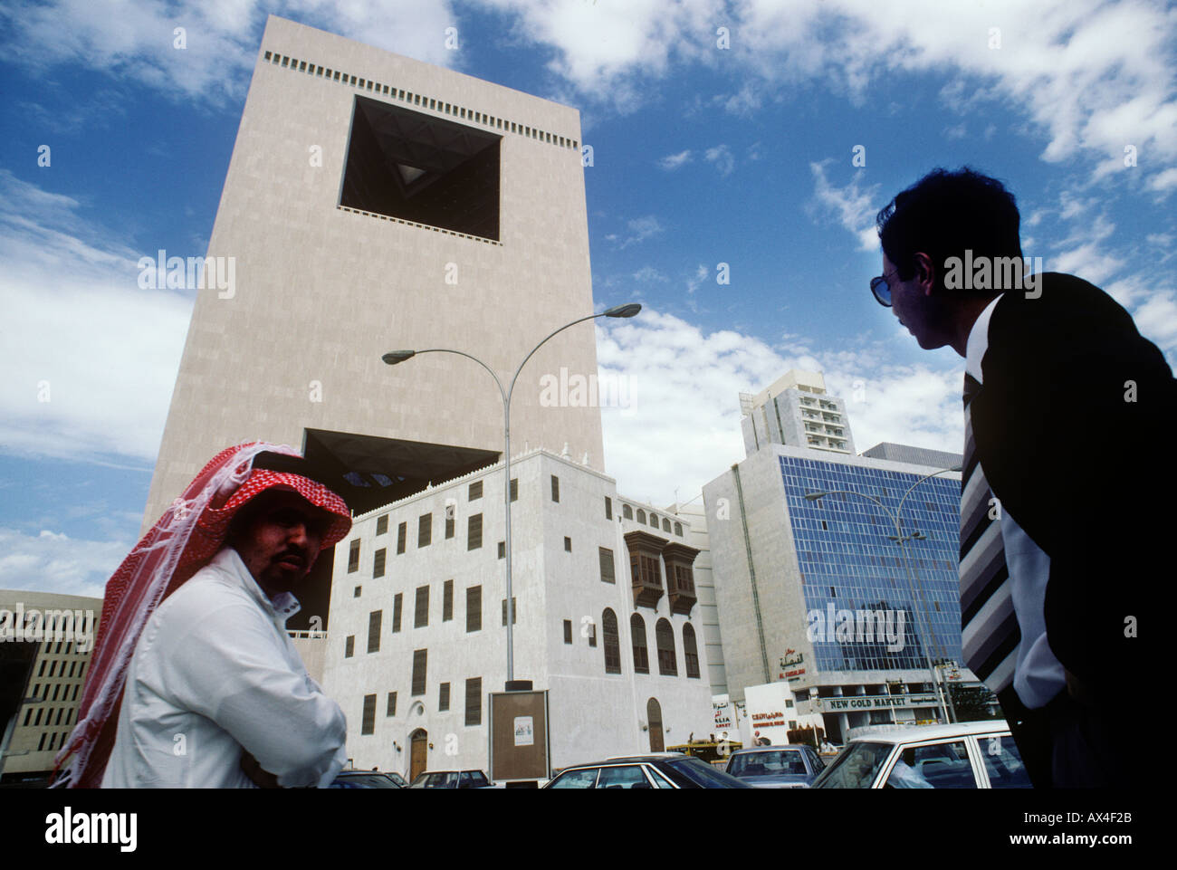 Arab men in traditional and western dress by the National Commercial Bank s building in Jeddah Saudi Arabia Stock Photo