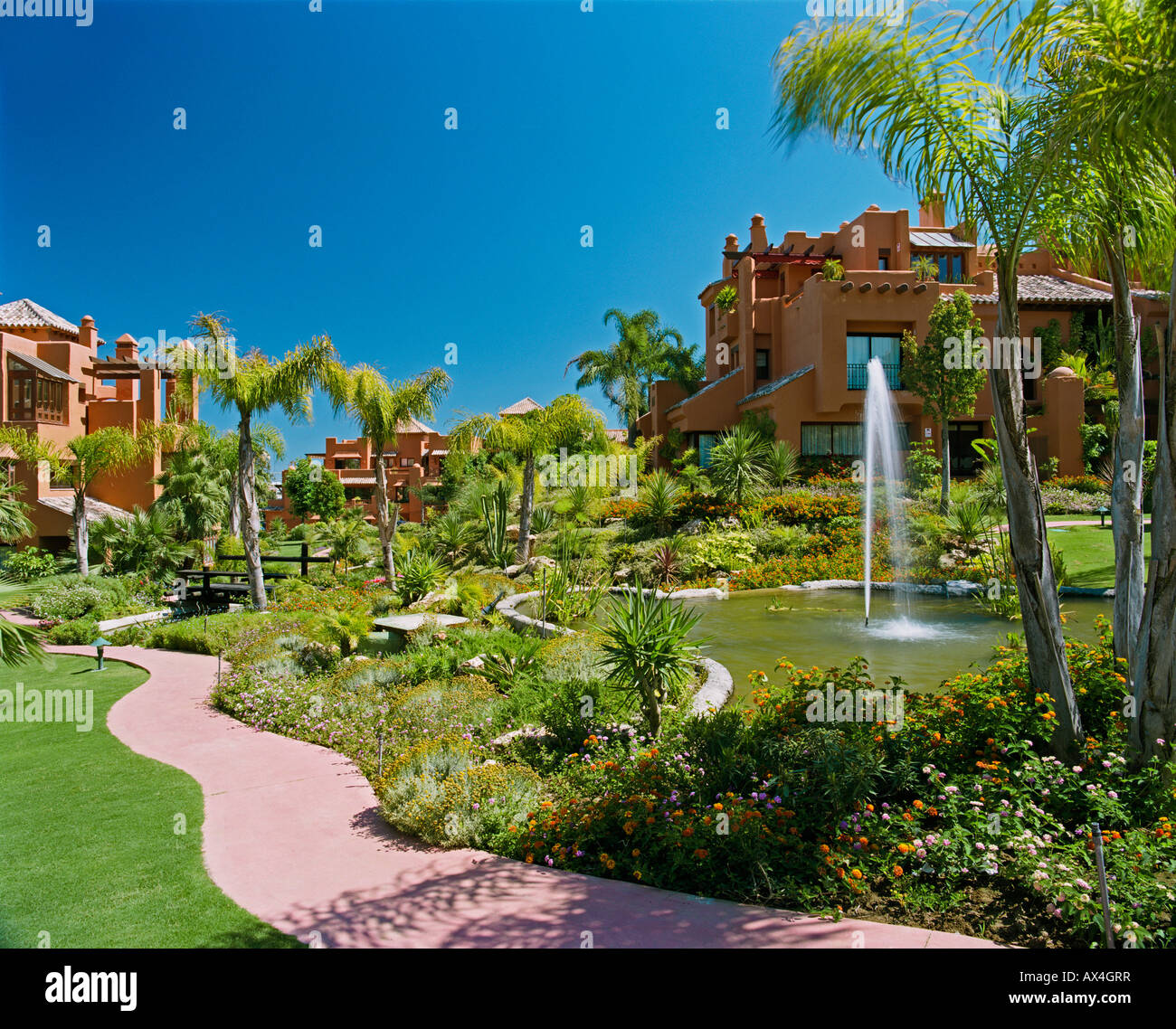 Fountain in pond and curved path in garden of newbuild Spanish holiday village Stock Photo