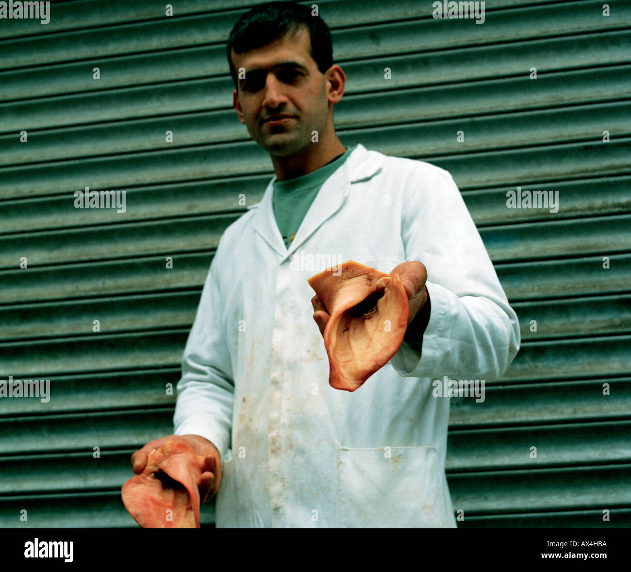 Butcher selling pig's ears in Green Street market, Upton Park, East London Stock Photo
