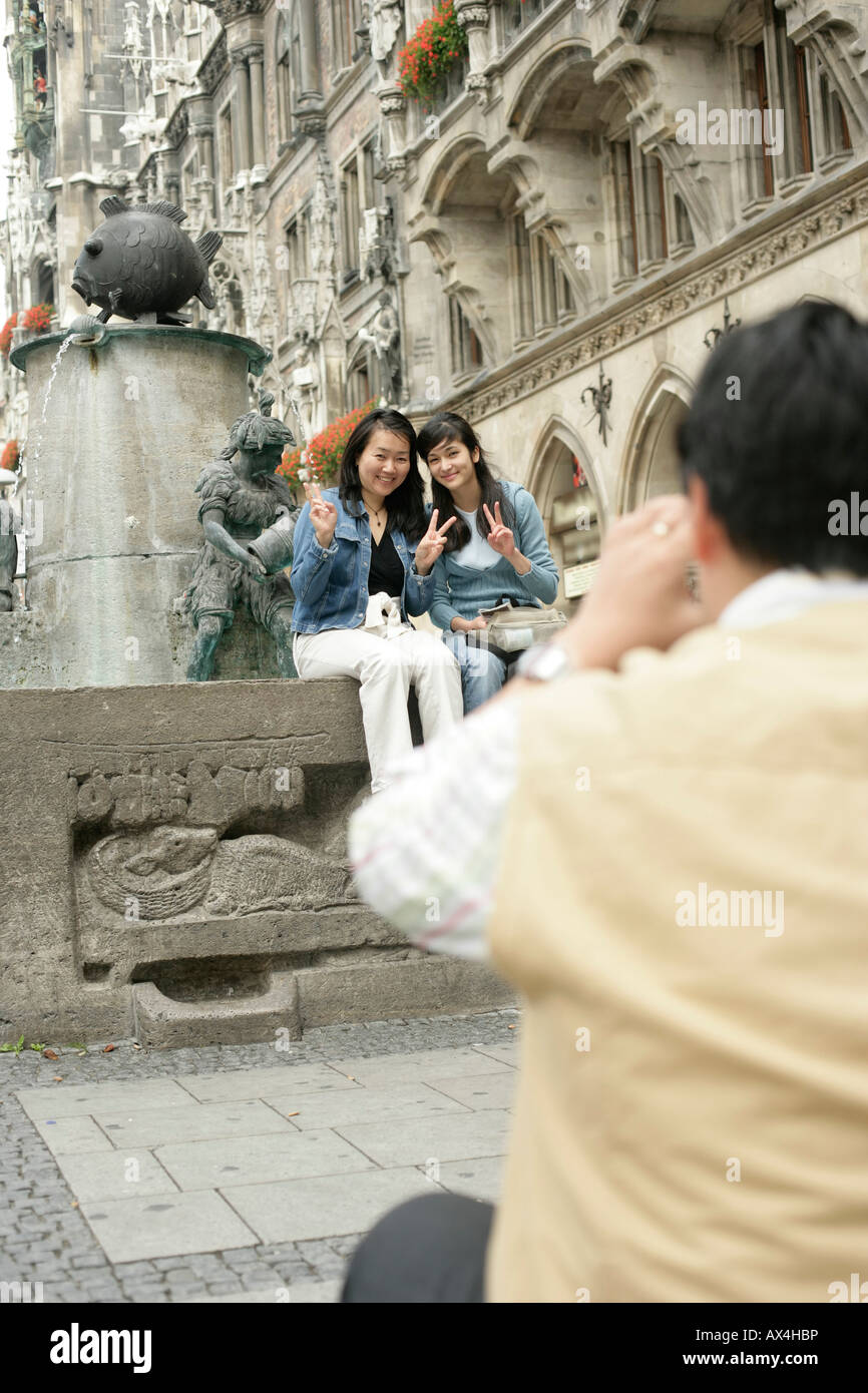 Two young Asian women sitting on the brim of a fountain Stock Photo - Alamy