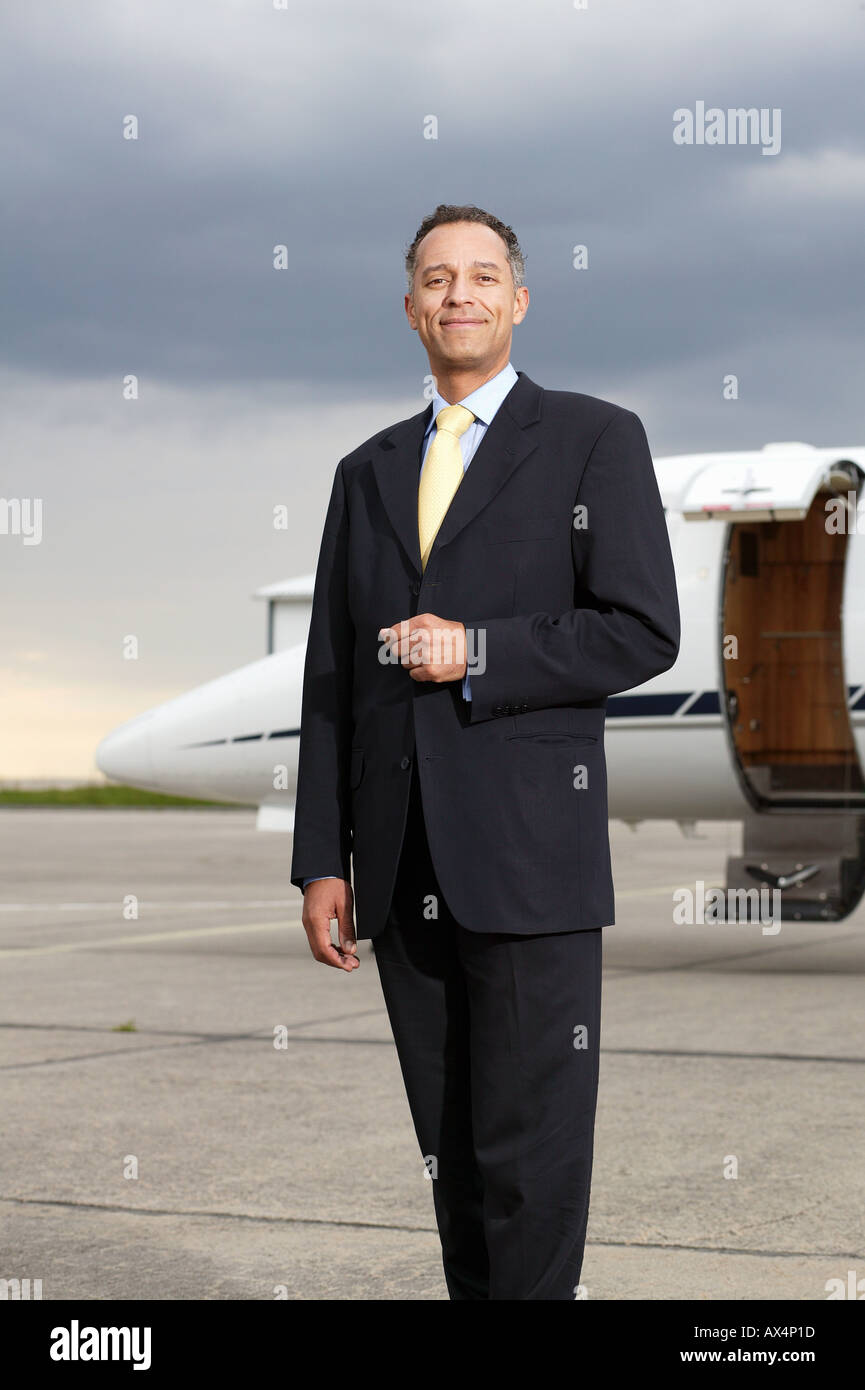 Businessman posing in front of a private airplane Stock Photo