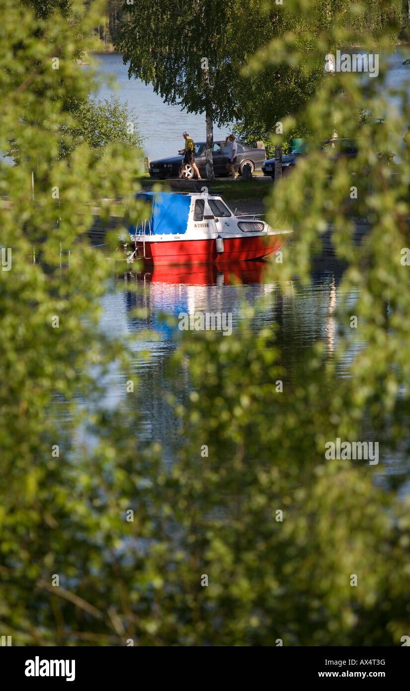 Motorboat and tourists at a small boat harbor / lay-by at lake Konnevesi Finland Stock Photo