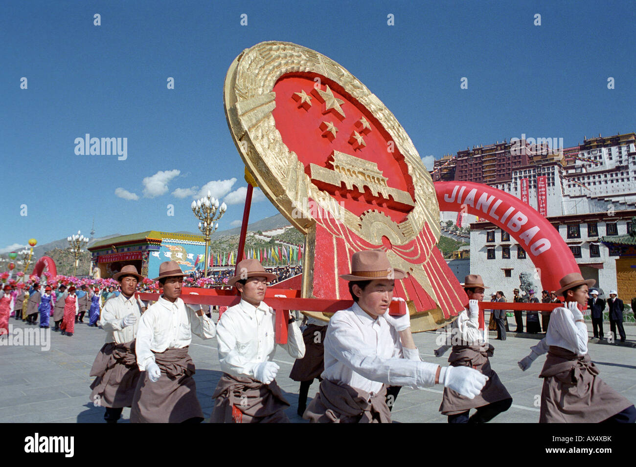 Tibetan hold a national emblem of the People's Republic of China in front of the Potala Palace during a ceremony in Lhasa.1995 Stock Photo