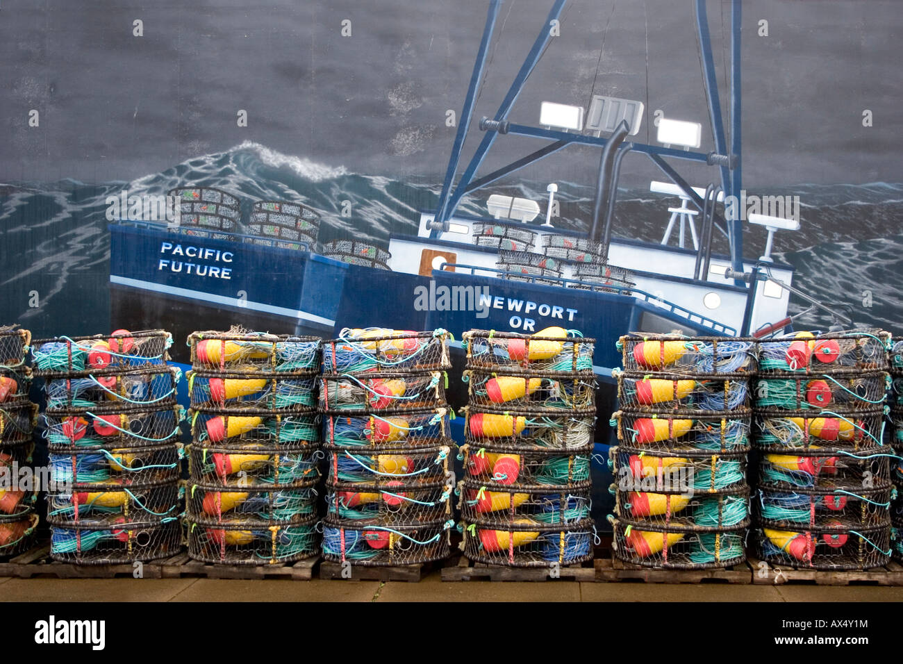 Crab pots stacked up in front of a fishing boat mural in Newport Oregon