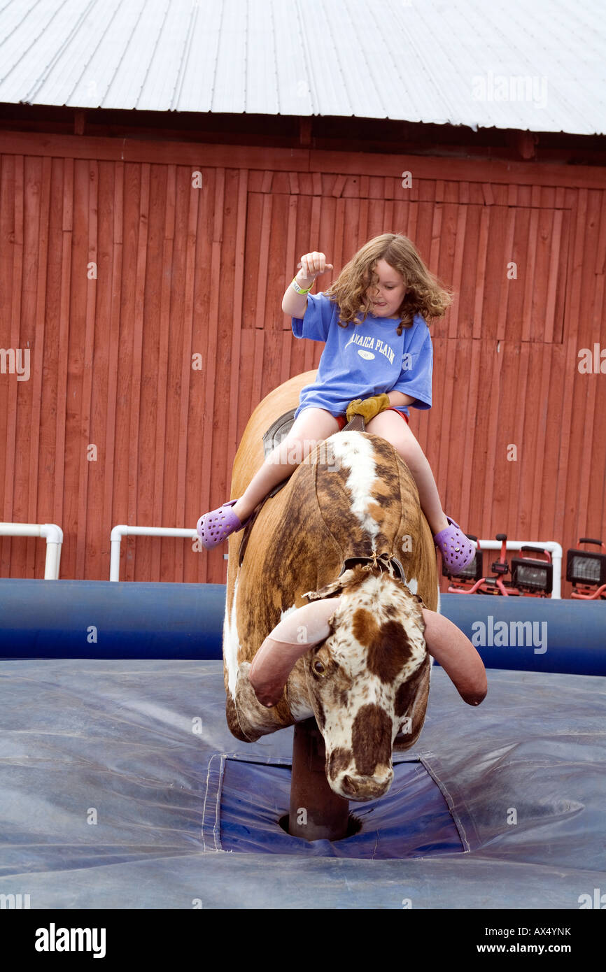 A young girl tries to stay on the mechanical bull on a summer day in Vermont. Stock Photo