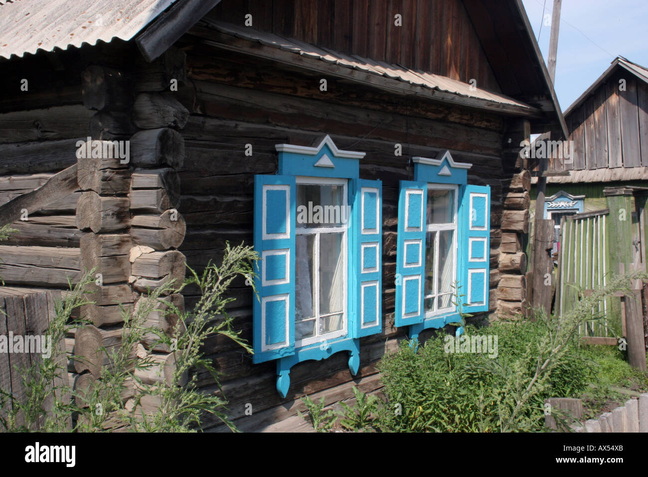 A Log Cabin Of Rough Wood And Blue Shutters On The Windows With