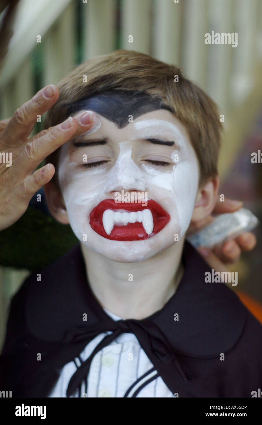 Mother puts on Halloween make up on preschooler boy dressed as Dracula. Stock Photo
