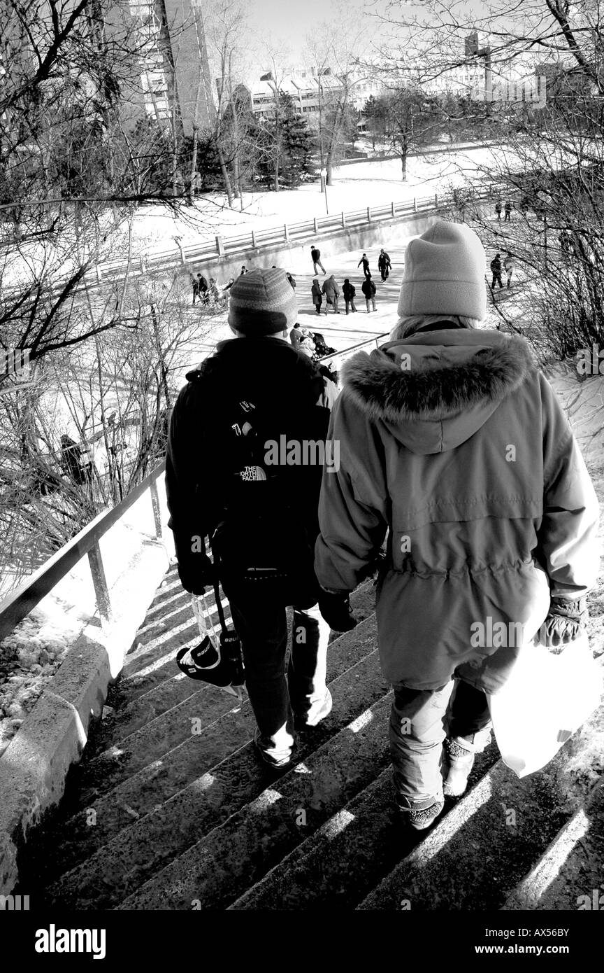 A pair of skaters walk down some steps towards the Rideau Canal Stock Photo