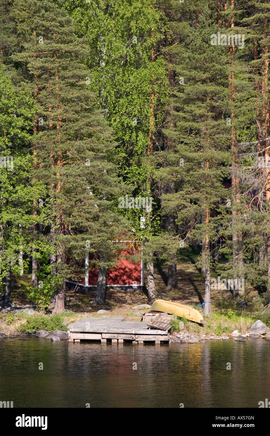 Small red sauna cabin hidden inside forest at waterfront Finland Stock Photo