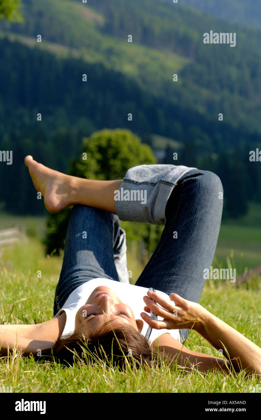 Woman lying in field using mobile phone Stock Photo