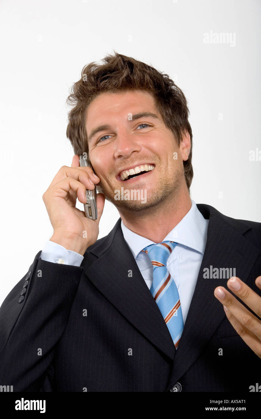 Young businessman using mobile phone, smiling, close-up Stock Photo