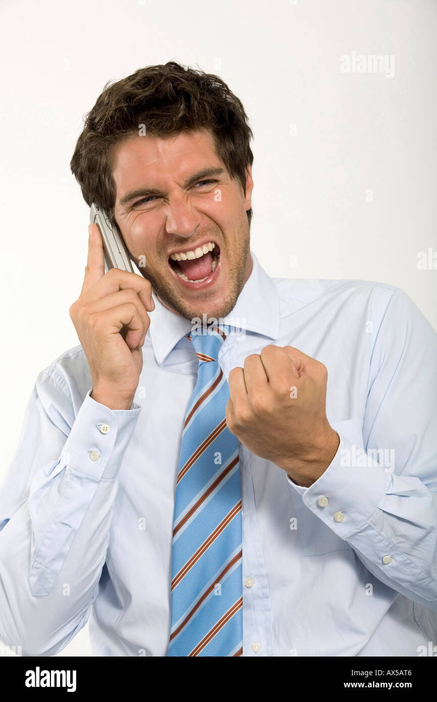 Young businessman using mobile phone, shouting, close-up Stock Photo