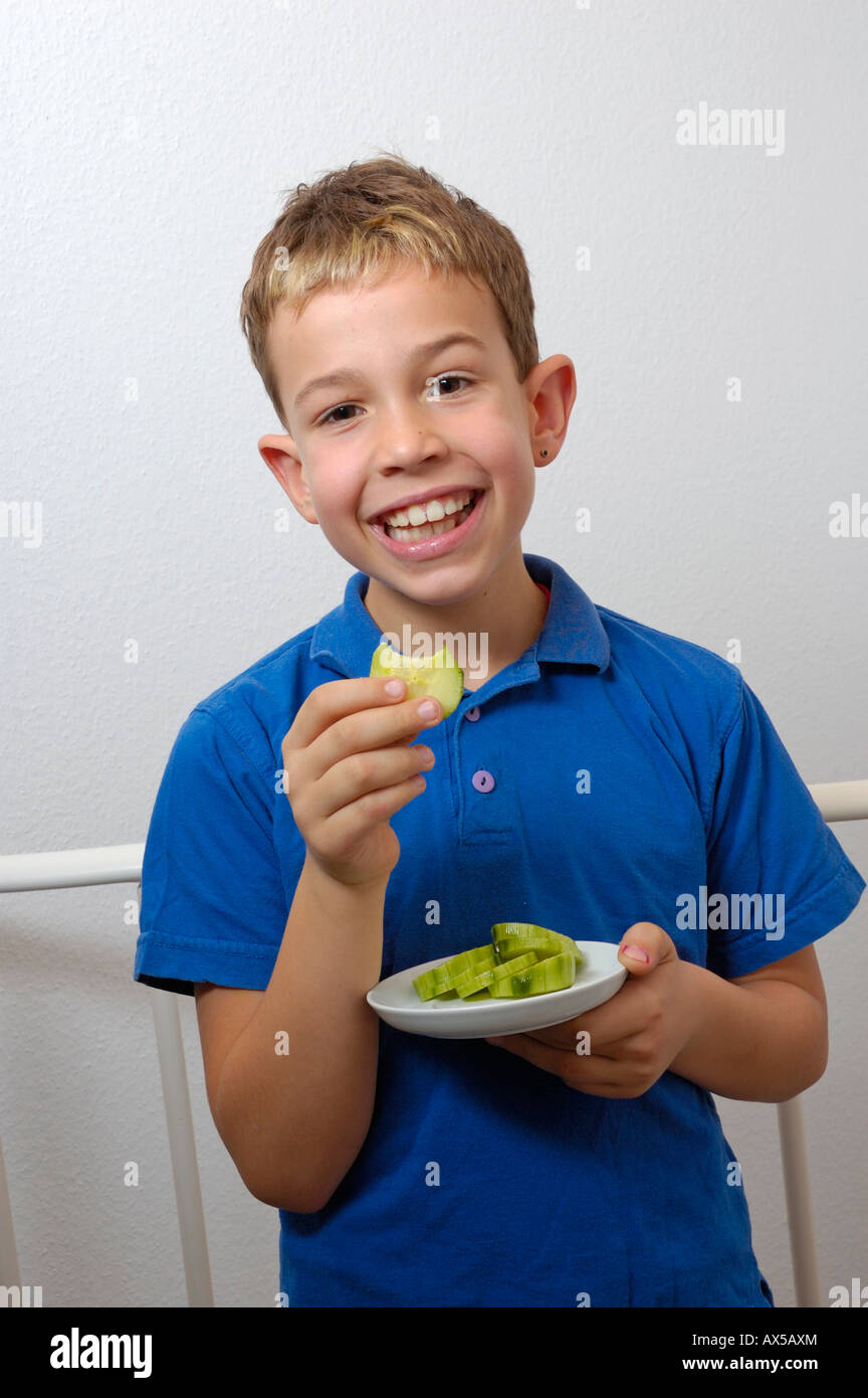Laughing boy holding a plate with cucumber slices Stock Photo