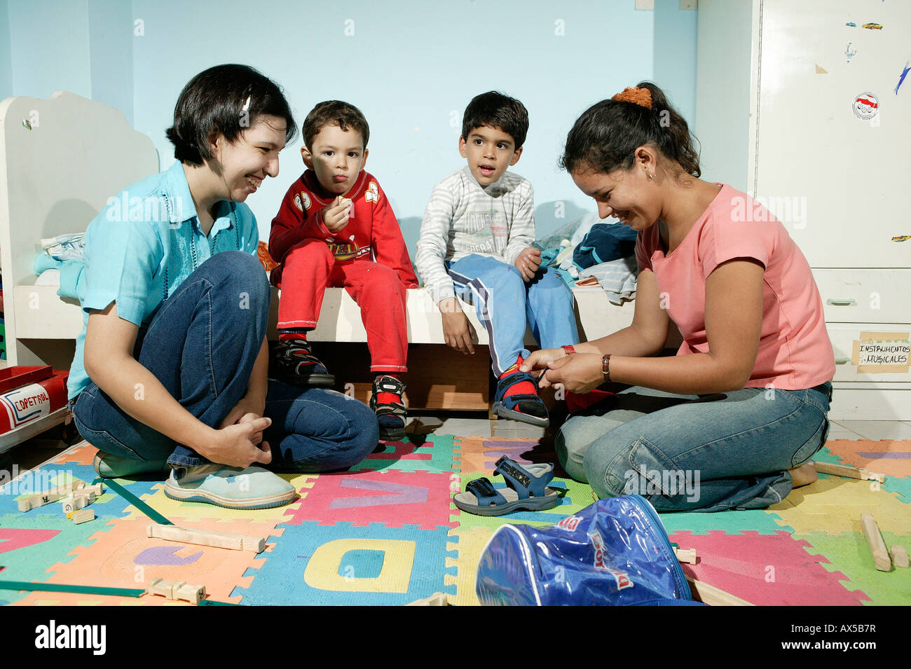 Women helping children getting dressed, Asuncion, Paraguay, South America Stock Photo