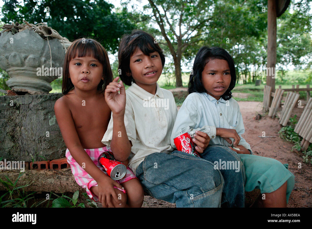 Kids with cans of Coca Cola posing for the picture in exchange for some money Killing Fields of Choeung Ek 15km from central P Stock Photo