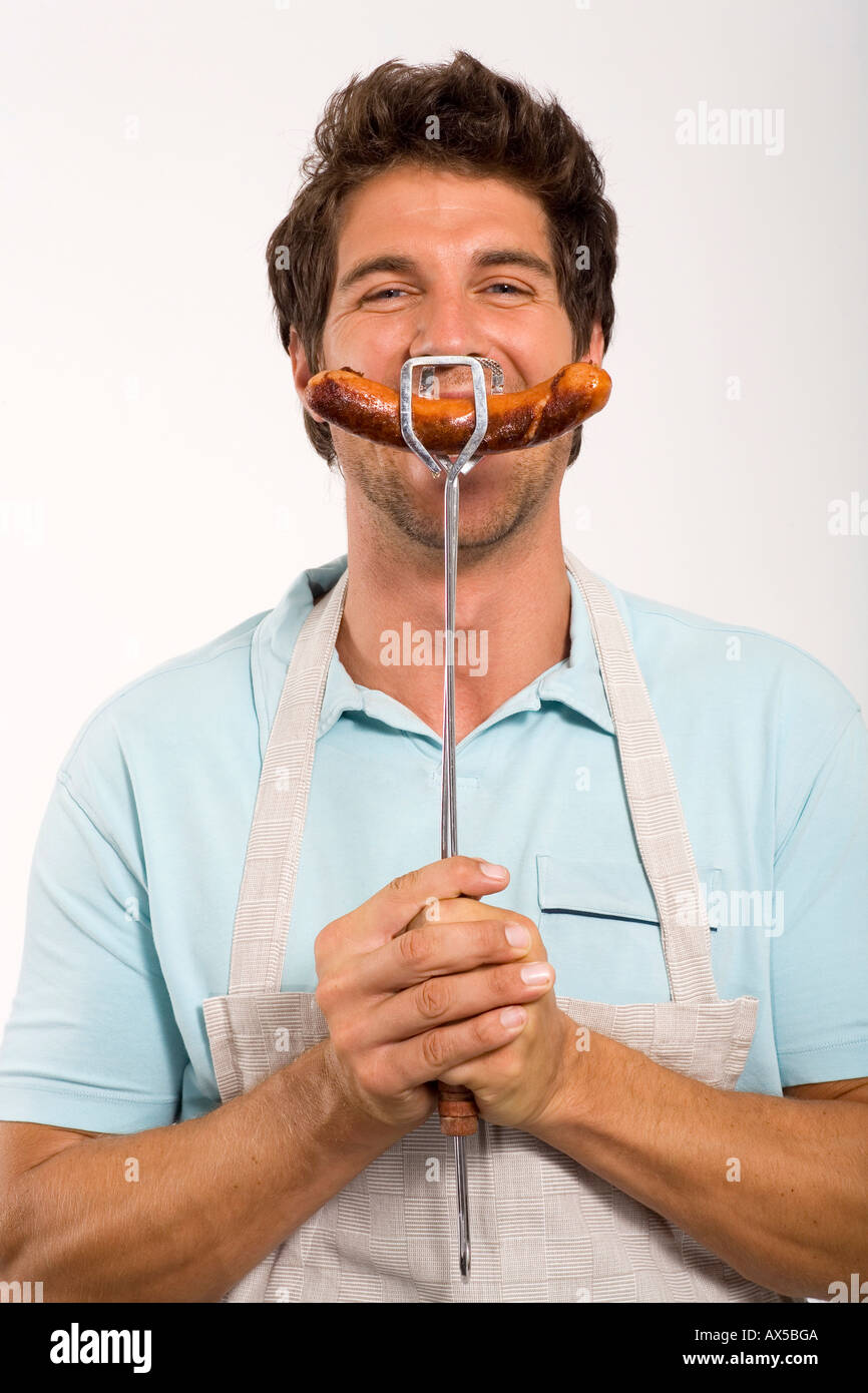 Young man holding grilled sausage, close up, portrait Stock Photo Alamy