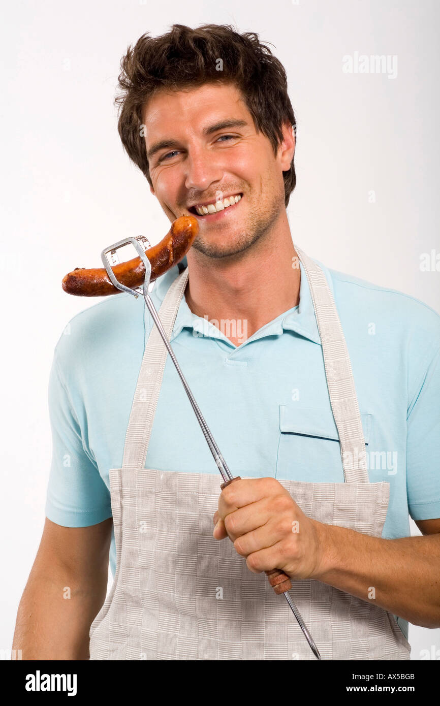 Young man holding grilled sausage, close up, portrait Stock Photo