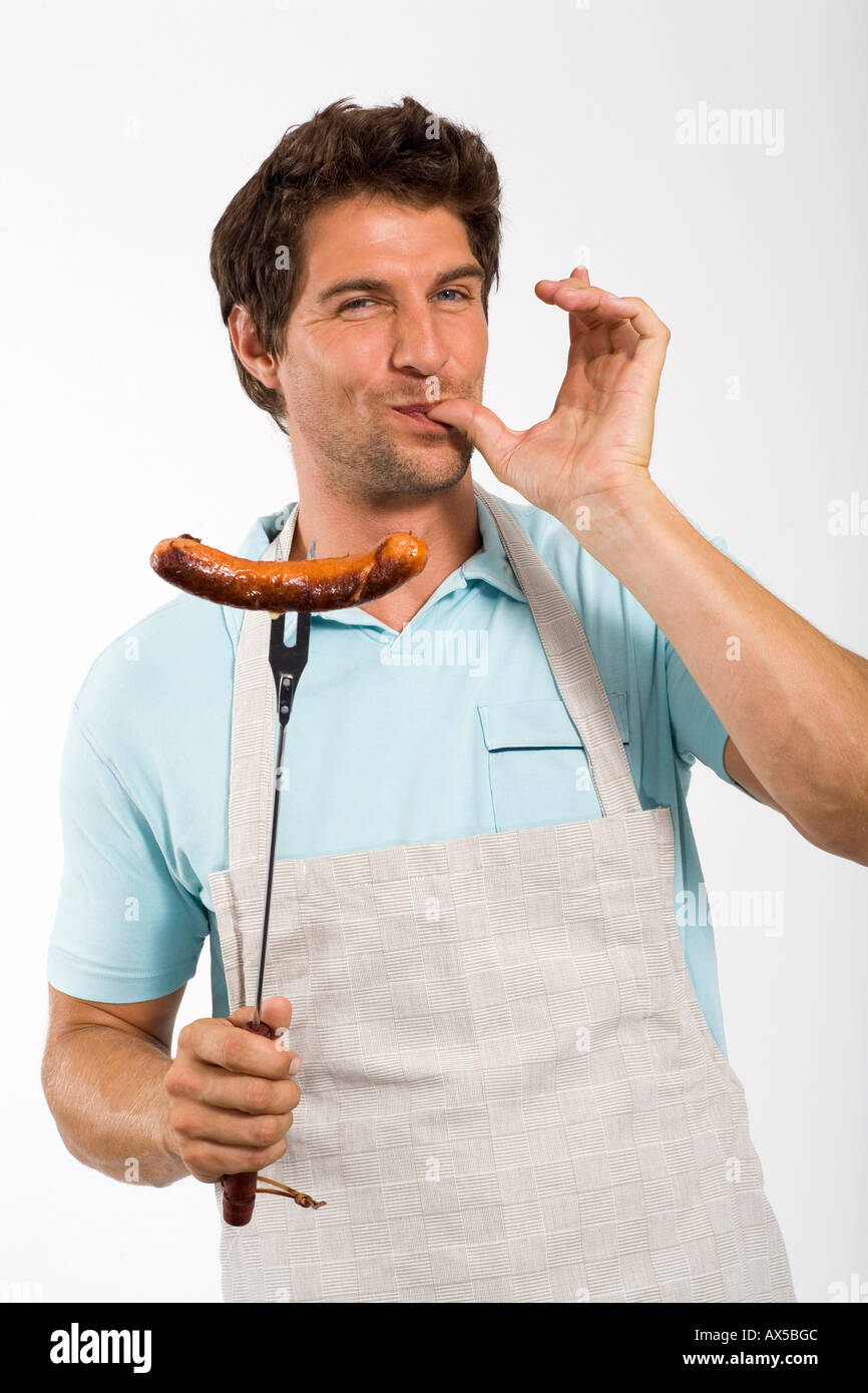 Young man with grilled sausage on fork, portrait Stock Photo