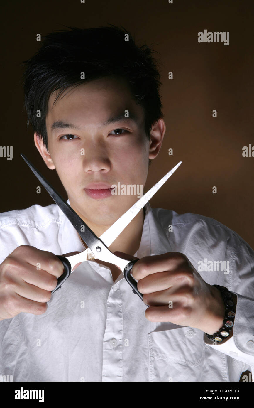 Young man holding opened scissors Stock Photo