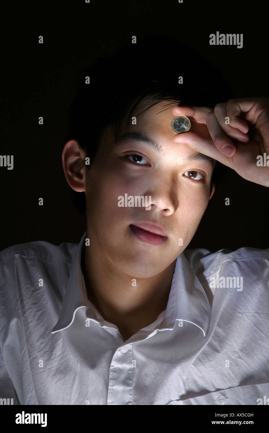 Young man holding a one euro coin to his forehead Stock Photo