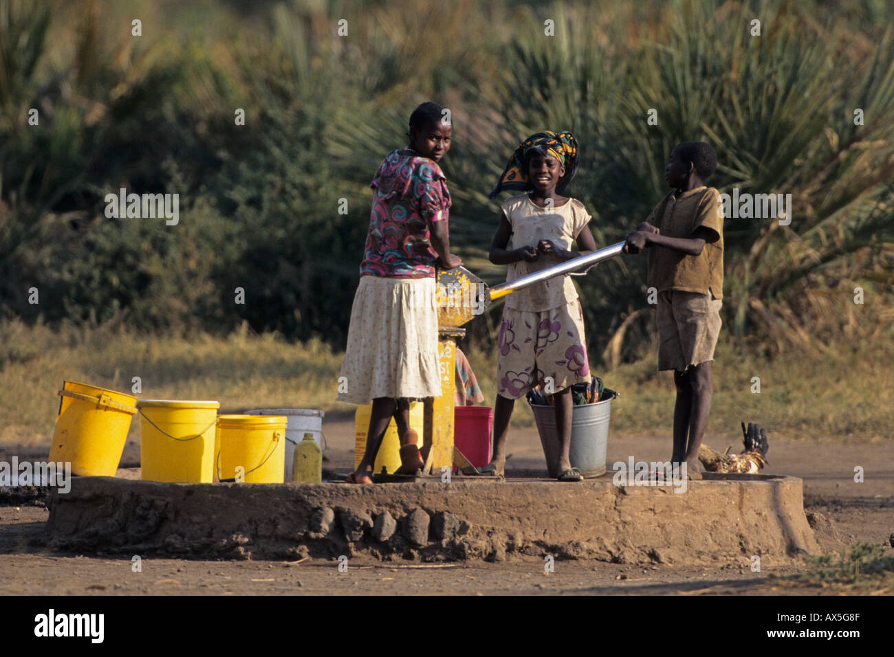 Children pumping drinking water at a village pump, Kifaru, Tanzania. Stock Photo