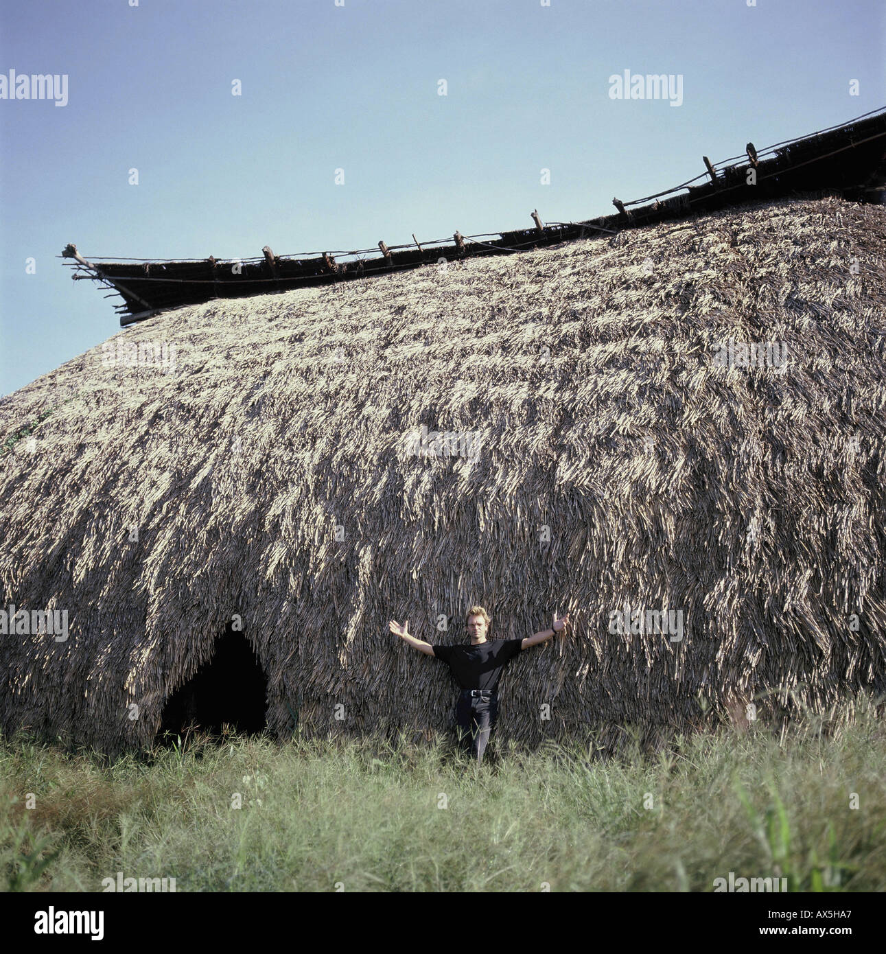 Pavuru Indian village, Brazil. Sting standing outside a large oca; Xingu Indigenous area; Nov 1990. Stock Photo