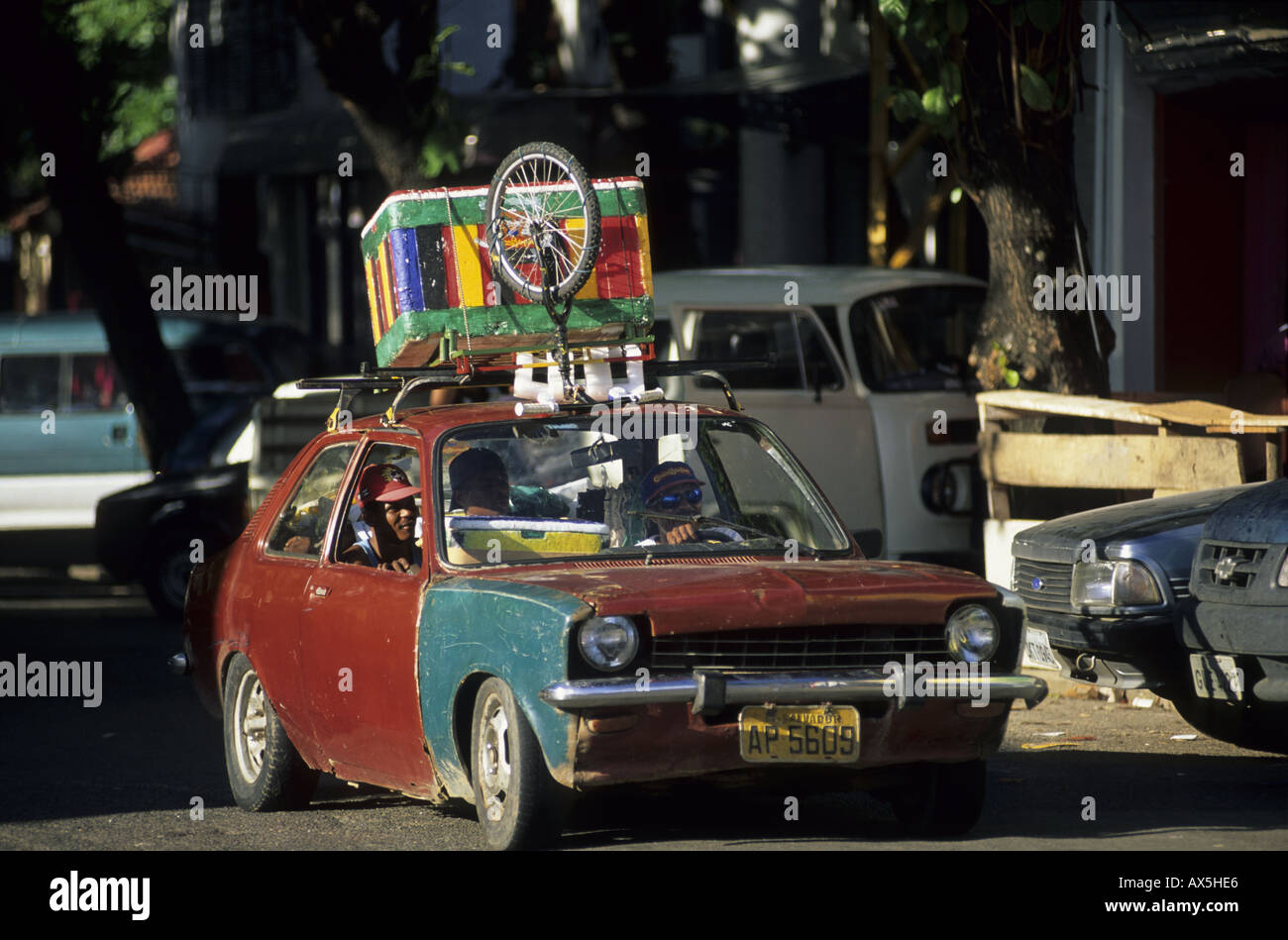 Salvador, Bahia State, Brazil. Very battered old Chrysler car with brightly painted box and bicycle on roof. Stock Photo