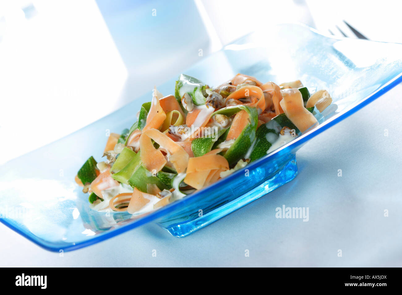 Salad with zucchini, carrots, pieces of walnut and yoghurt dressing Stock Photo