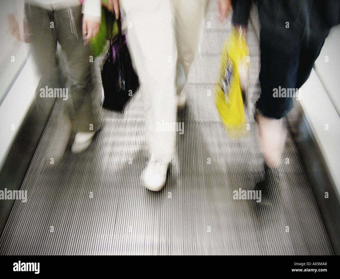 Close-up of blurred legs walking on a moving walkway at an airport or station. Stock Photo