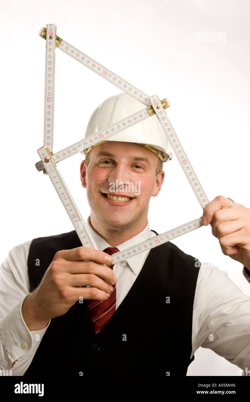 Man dressed in suit holding yardstick shaped into a house Stock Photo