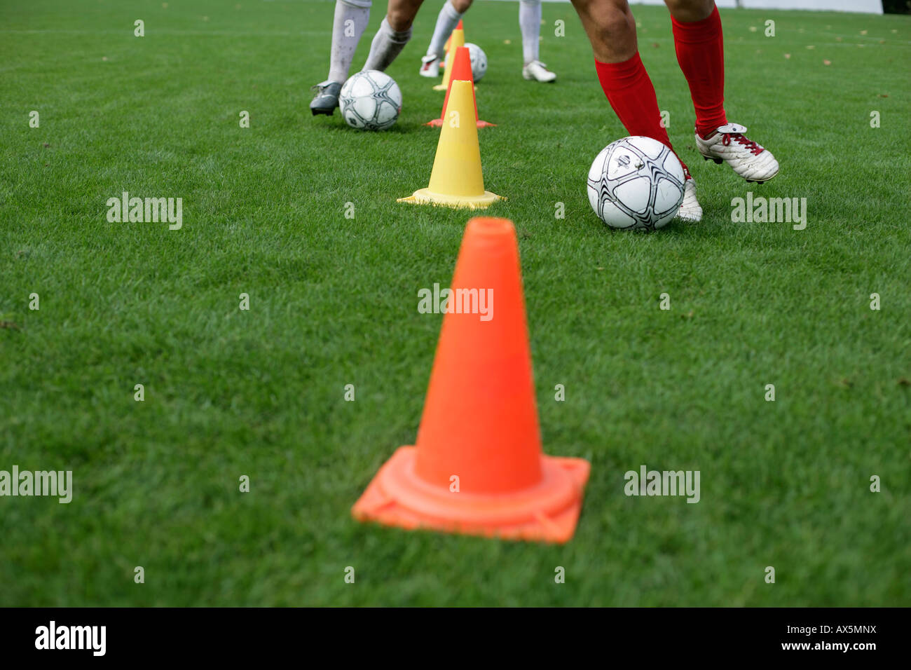 Soccer player running slalom with football around marks Stock Photo