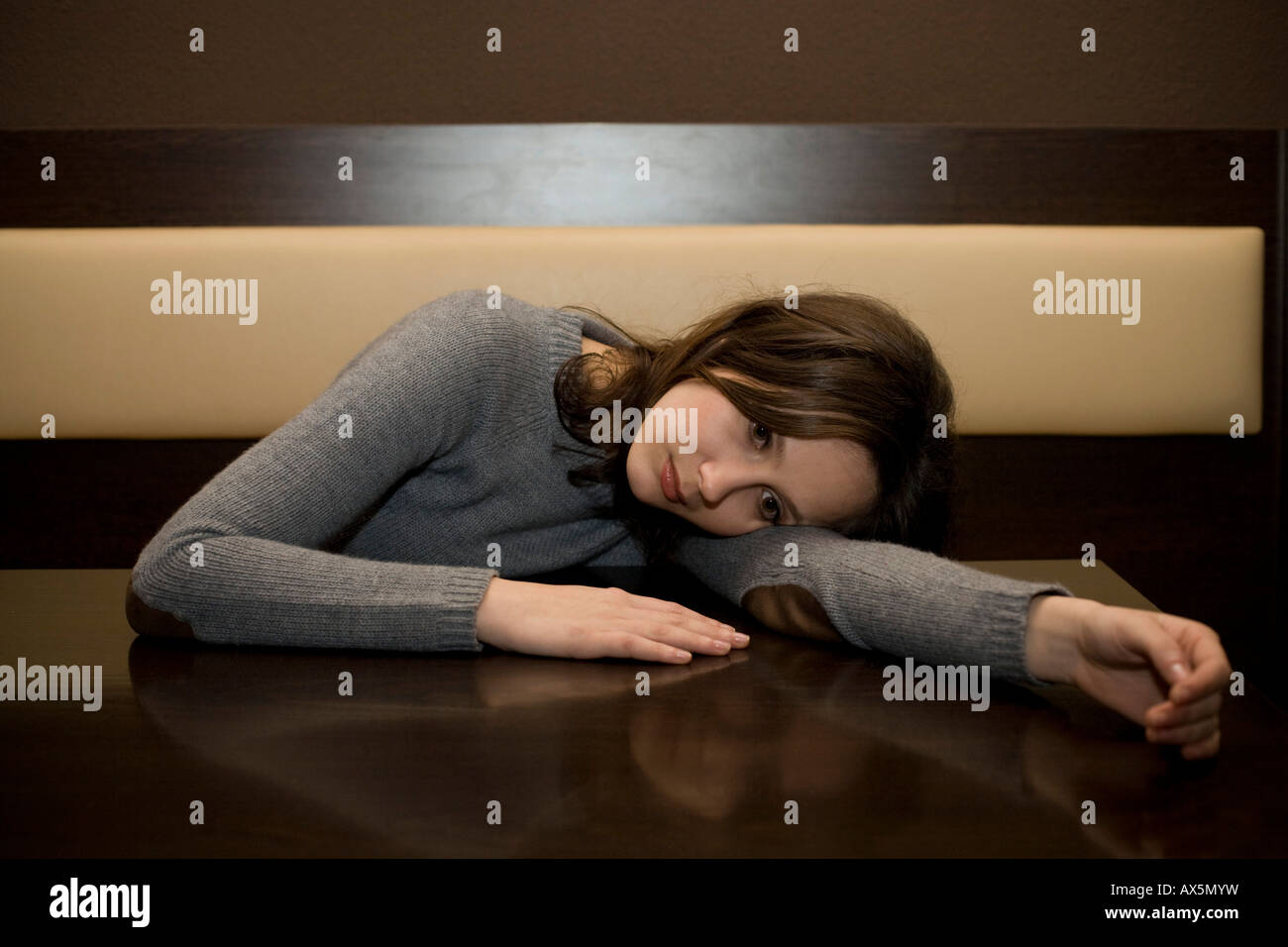 Young woman leaned over a table at a bar, looking depressed Stock Photo