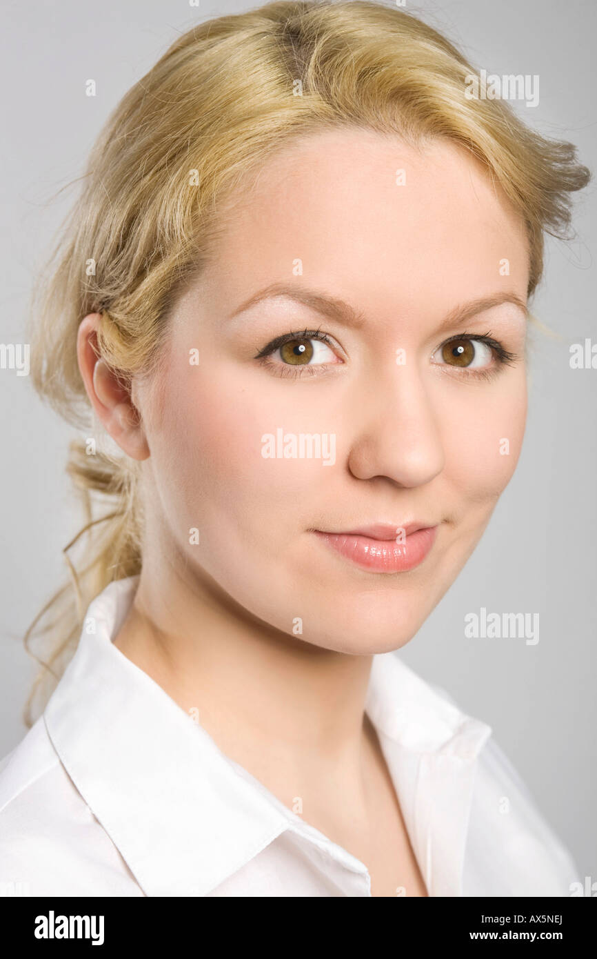 Portrait of a young blonde woman wearing a white blouse, smiling Stock Photo