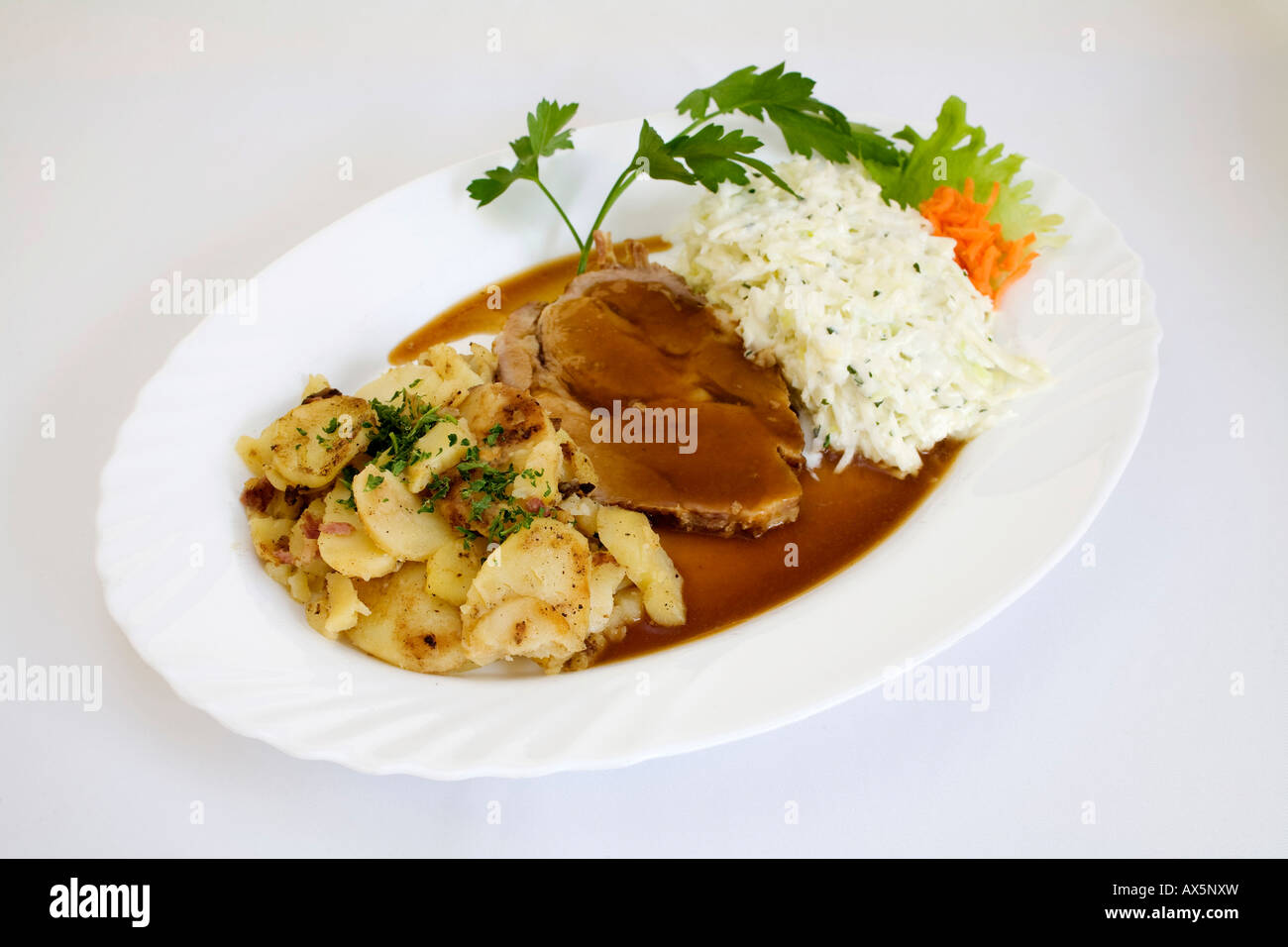 Pork roast with gravy, coleslaw and roasted potatoes Stock Photo
