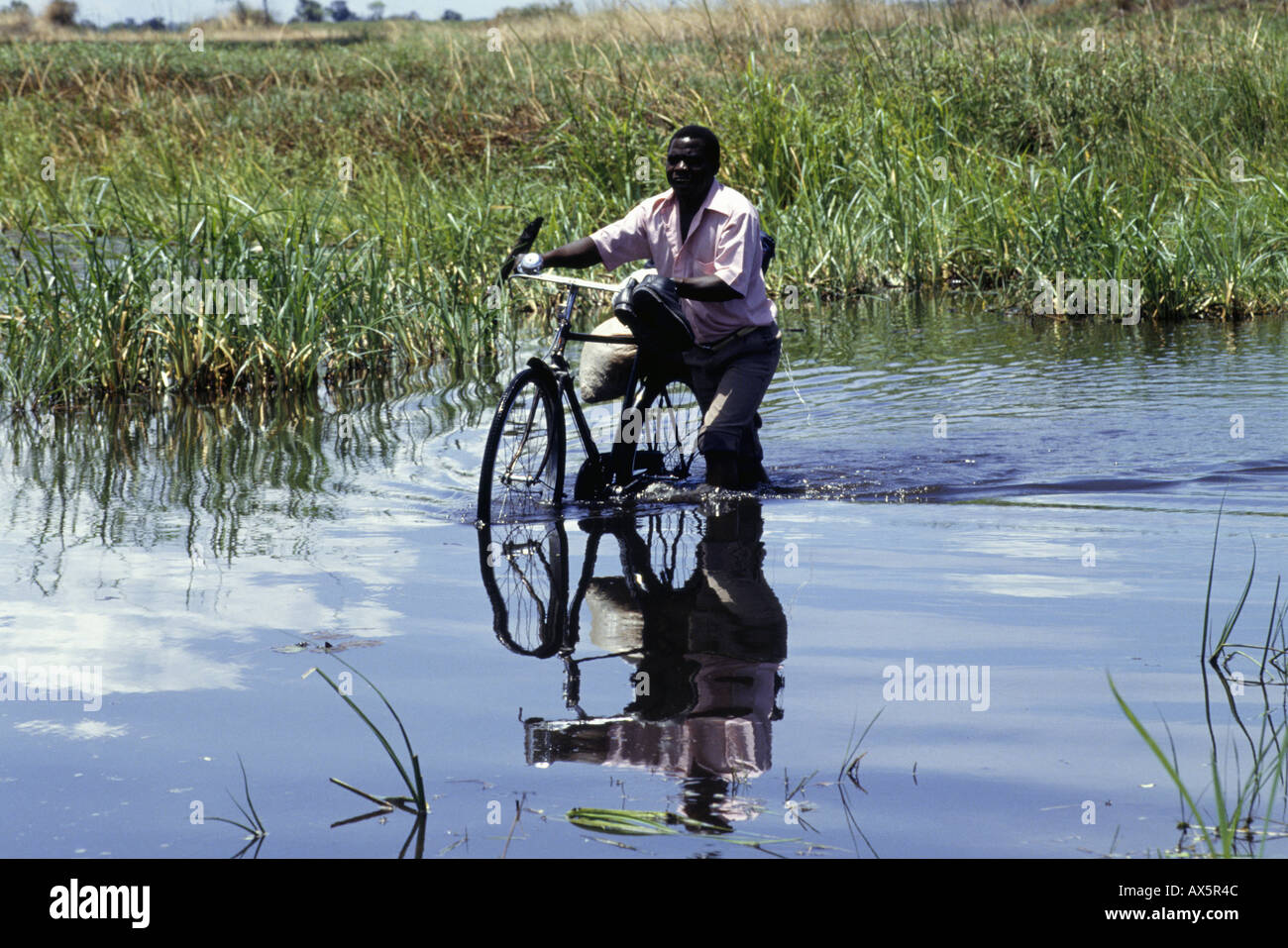 chipundu-zambia-man-wheeling-bicycle-loaded-with-sacks-through-water