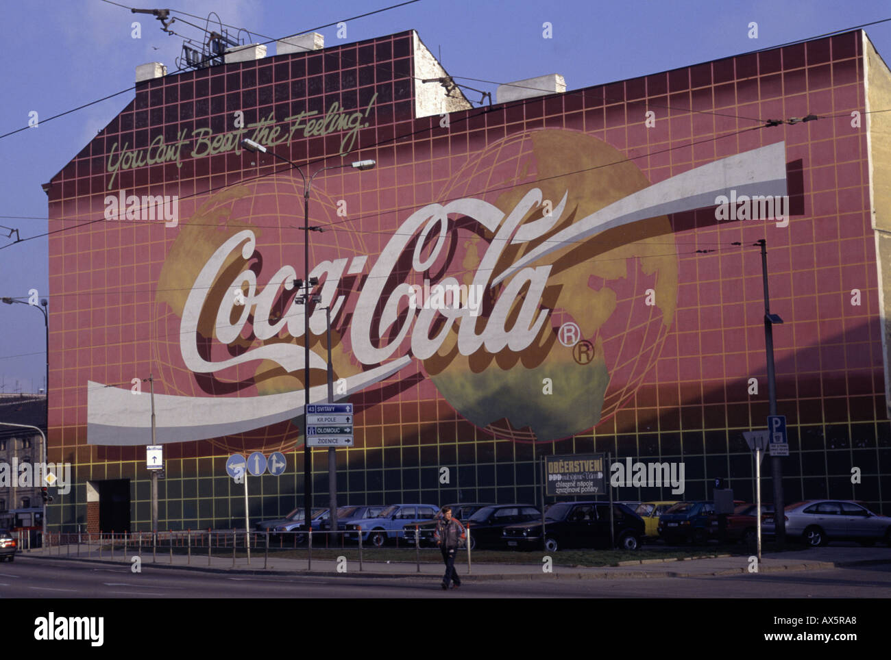 Prague, Czech Republic. Massive 'Coca - Cola' advertisement on a wall; signs in Czech under; cars parked. Stock Photo