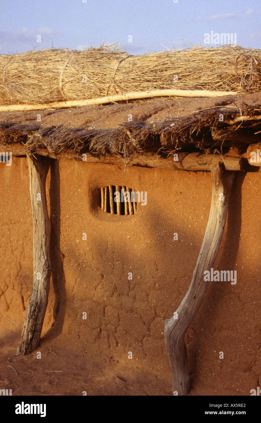 Dodoma, Tanzania. Thatched unpainted adobe house with window barred with rough sticks. Stock Photo