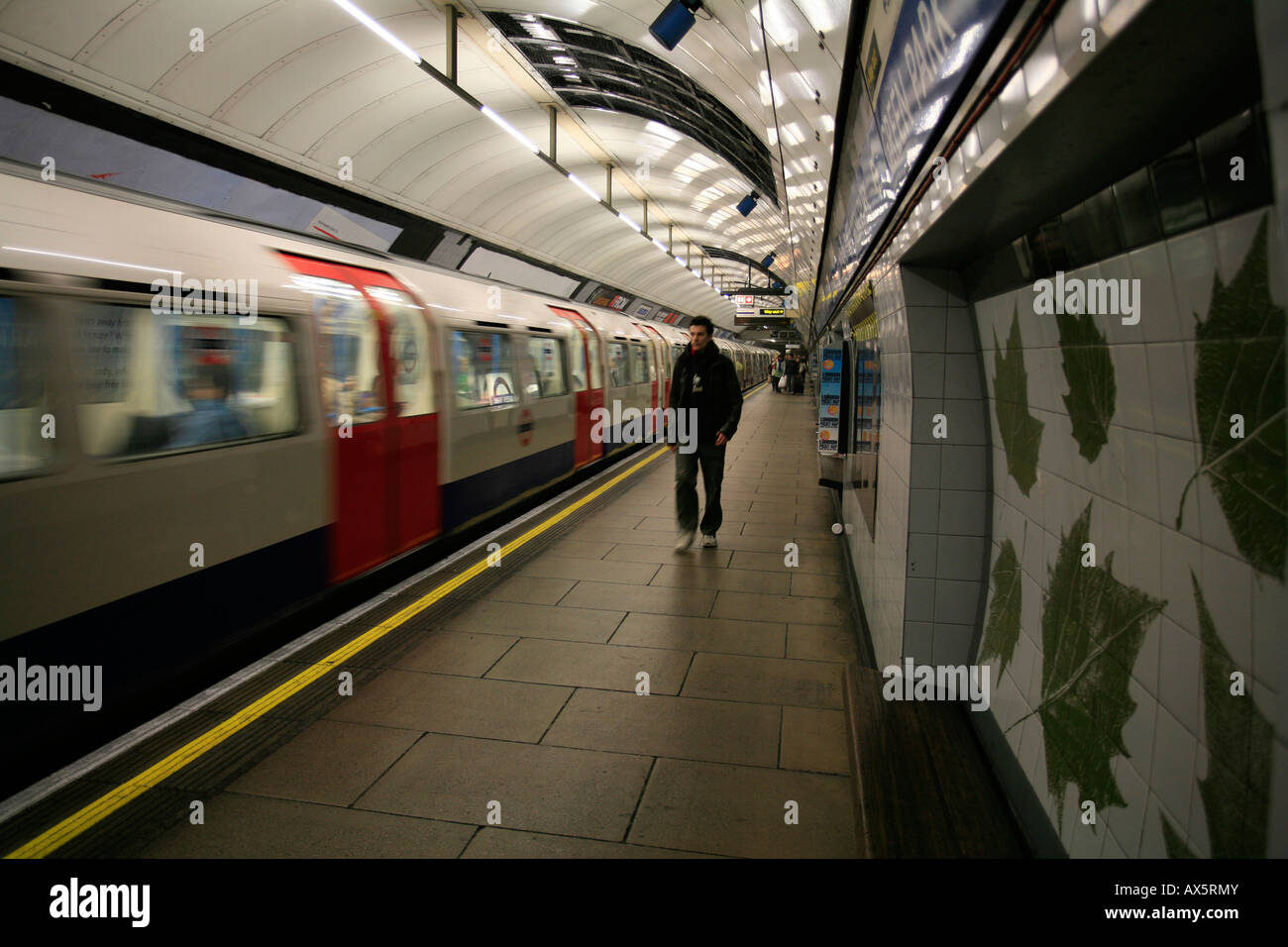 Tube logo, green leaves on wall tiles and train arrived at Green Park underground station, London, England, UK, Europe Stock Photo