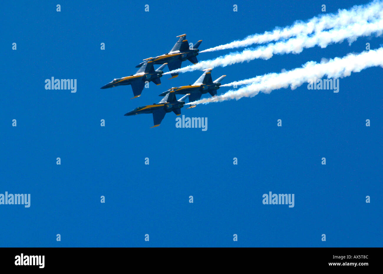 The Blue Angels FA 18s fly in tight formation with trails of white smoke against a clear blue sky Stock Photo