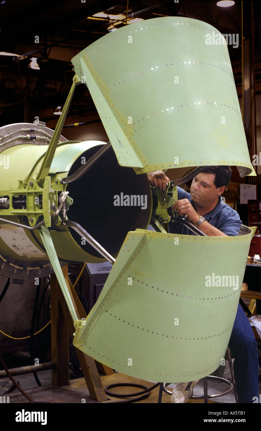 A worker putting the finishing touches on a green primered engine braking thrust inverter assembly Stock Photo