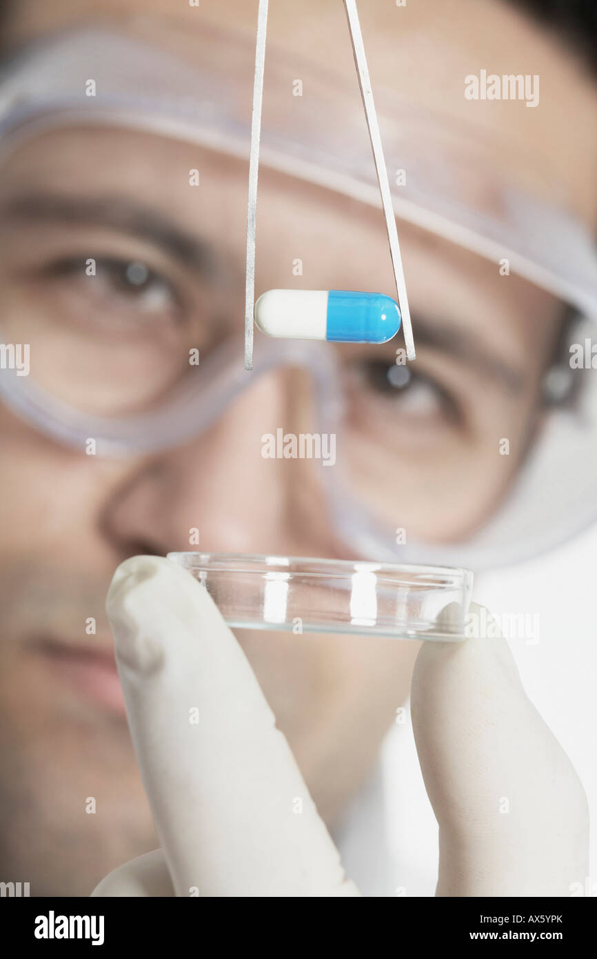 Chemist holding pill with tweezers Stock Photo