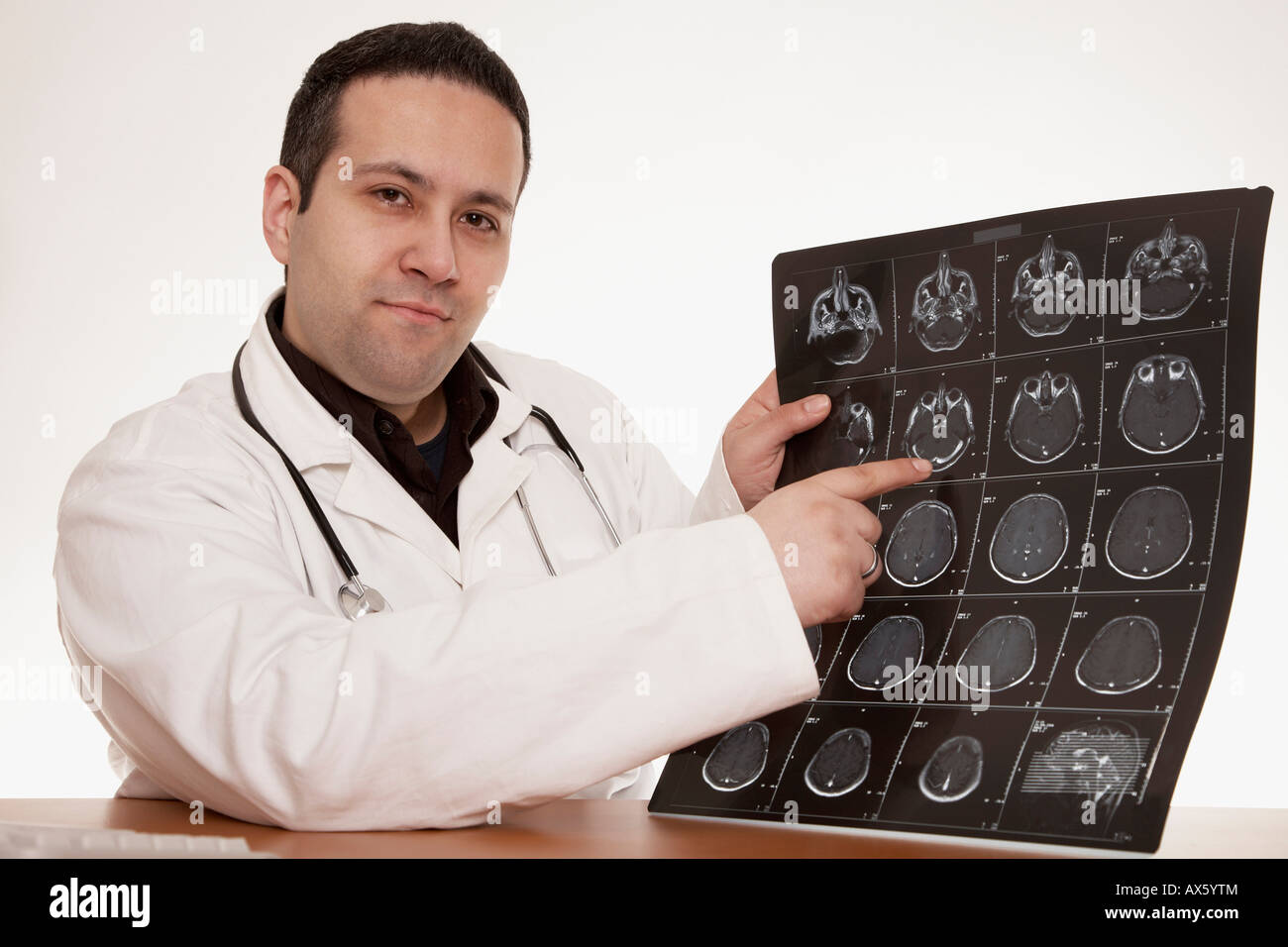 Physician with stethoscope pointing to a CT scan image of a skull Stock Photo