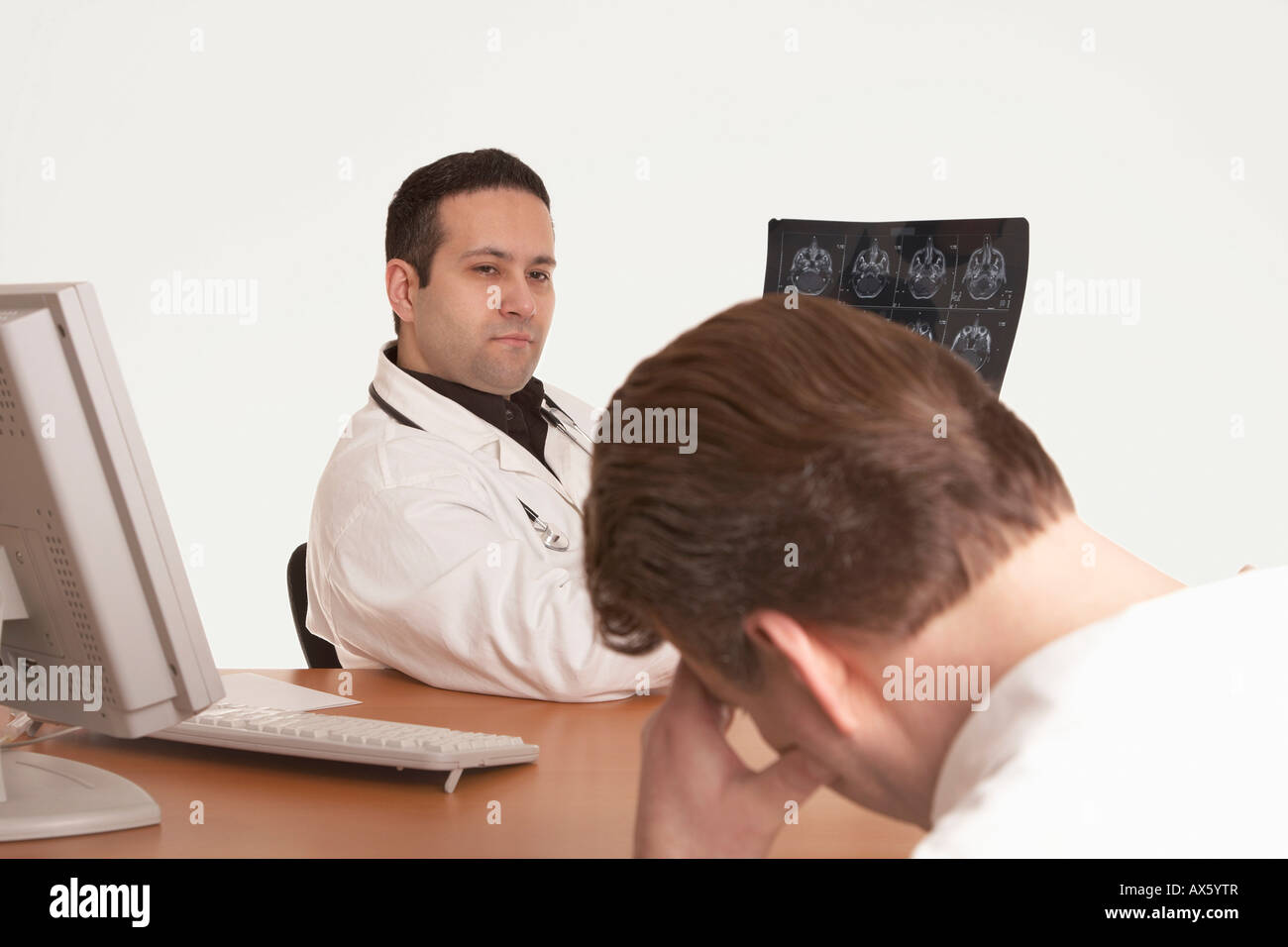 Physician with stethoscope showing CT scan image, delivering diagnosis to patient Stock Photo