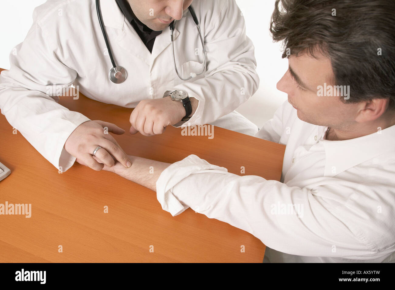 Physician with stethoscope checking patient's pulse Stock Photo