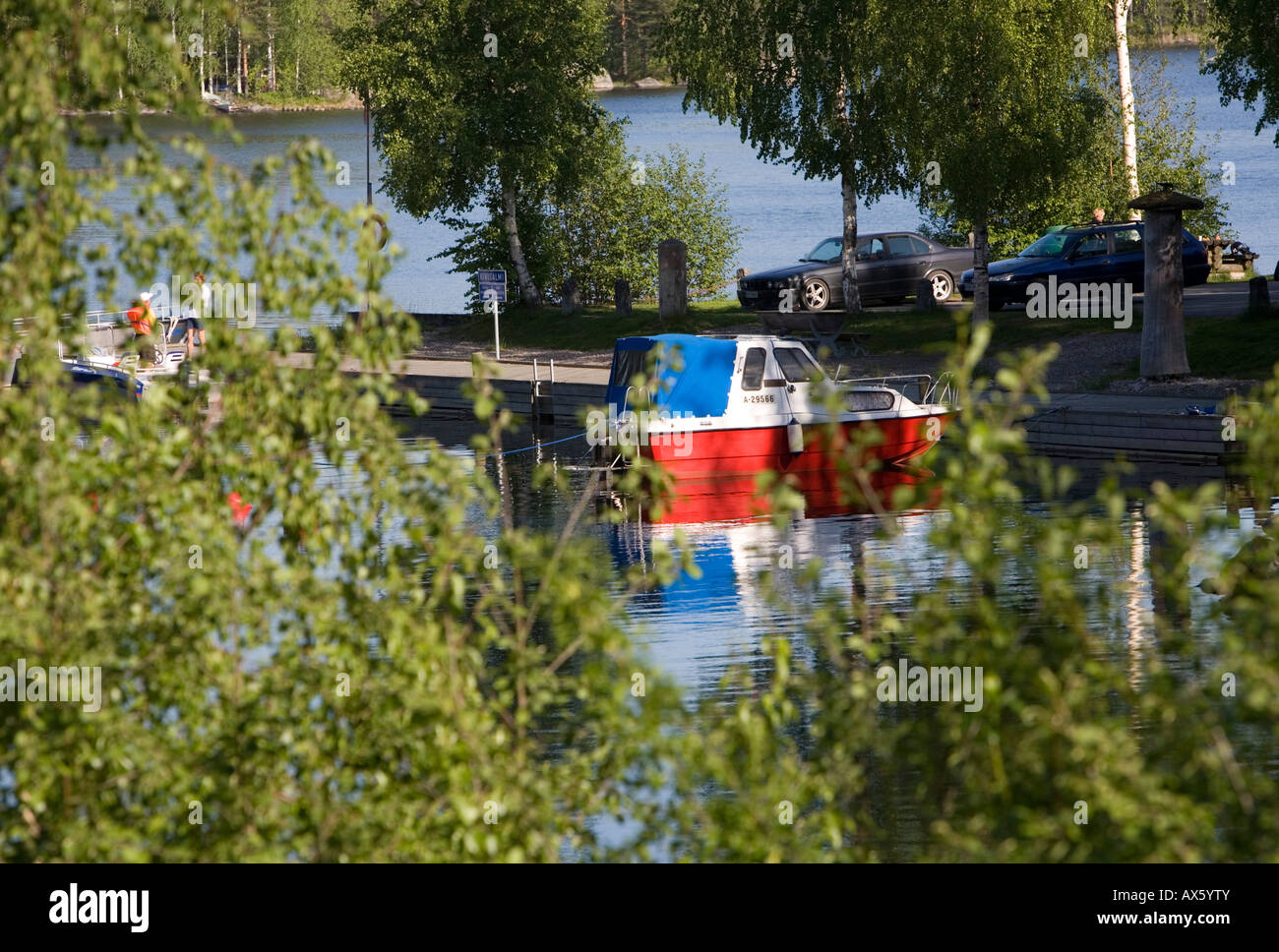 Motorboat / skiff and tourists at a small boat harbor at lake Konnevesi Finland Stock Photo