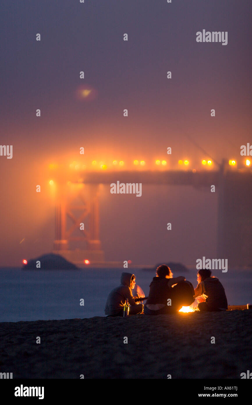 Group of girls hanging out around campfire on Baker Beach playing music