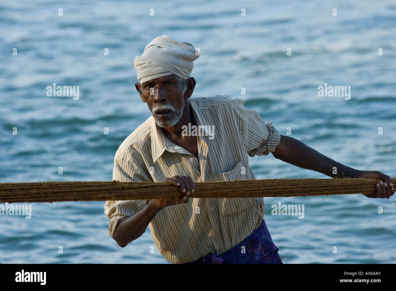 Elderly Man Pulling in Fishing nets on the Beach in Varkala India Stock Photo