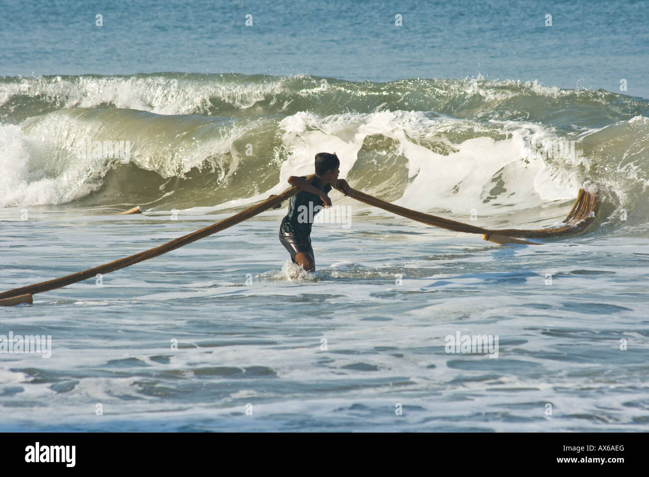 Man in the Ocean Pulling in Fishing nets on the Beach in Varkala India Stock Photo