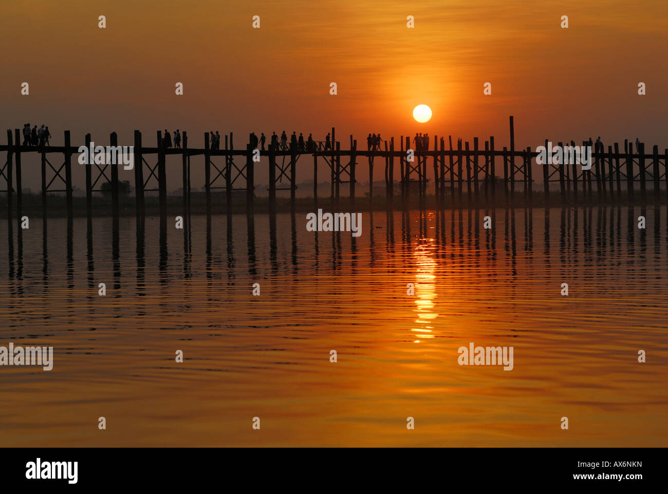 Silhouette of group of people walking on bridge across river at dusk U ...